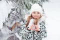 Portrait of little girl on background of Christmas tree in snow winter forest, showing love heart shape with her fingers Royalty Free Stock Photo