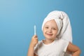 Portrait of a little girl on a blue background. A child with a white towel on his head holding a toothbrush. The concept of daily Royalty Free Stock Photo