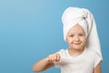 Portrait of a little girl on a blue background. A child with a white towel on his head holding a toothbrush. The concept of daily Royalty Free Stock Photo