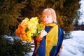 Portrait of Little girl in blue coat, yellow scarf and bouquet of flowers in winter or spring in nature in the Royalty Free Stock Photo