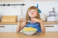 Portrait of a little girl in a blue dress funny eats a spaghetti