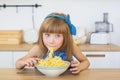 Portrait of a little girl in a blue dress funny eats a spaghetti from a dish