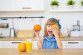 Portrait of a little girl in a blue dress plays with an oranges on a table Royalty Free Stock Photo