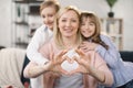 Portrait of little girl and boy and mother join hands forming heart shape as concept of giving love. Royalty Free Stock Photo