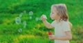 Portrait little girl child blowing soap bubbles in summer park Royalty Free Stock Photo