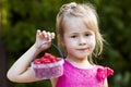 Portrait of a little girl child holdind small basket of ripe raspberries. Close-up Royalty Free Stock Photo