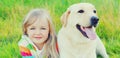 Portrait little girl child and labrador retriever dog together on the grass in summer Royalty Free Stock Photo