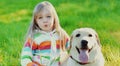 Portrait little girl child and labrador retriever dog together on the grass in summer Royalty Free Stock Photo