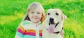 Portrait little girl child and labrador retriever dog together on the grass in summer Royalty Free Stock Photo