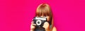 Portrait of little girl child with vintage film camera taking picture on pink background Royalty Free Stock Photo