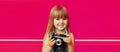 Portrait of little girl child with vintage film camera taking picture on pink background Royalty Free Stock Photo