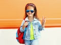 Portrait of little girl child wearing a backpack, sunglasses, jeans jacket on city street Royalty Free Stock Photo