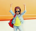 Portrait of little girl child wearing a backpack, sunglasses, jeans jacket on city street Royalty Free Stock Photo