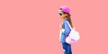 Portrait of little girl child wearing baseball cap with backpack looking away on pink background, blank copy space for advertising Royalty Free Stock Photo