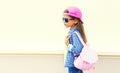 Portrait of little girl child wearing baseball cap with pink backpack on city street background Royalty Free Stock Photo