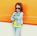 Portrait of little girl child wearing a sunglasses, jeans jacket on city street Royalty Free Stock Photo