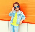 Portrait of little girl child wearing a sunglasses, jeans jacket on city street Royalty Free Stock Photo