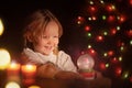 portrait of little girl in dark room looks at glass ball and laughs. christmas, happy childhood concept