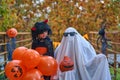 Portrait little girl in devil witch costume laughs with ghost wearing glasses. Orange pumpkin Halloween. A holiday on Royalty Free Stock Photo