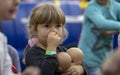 Portrait of a little girl with dolls picking her nose with her finger. Childish thoughtfulness and spontaneity.