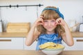 Portrait of a little girl funny eats a spaghetti from a dish and smiling