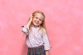 Portrait of little girl in headphones. schoolgirl in uniform. pink background