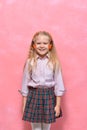 Portrait of little girl in headphones. schoolgirl in uniform. pink background