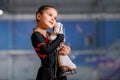 Portrait of little girl holding figure skates standing by ice rink Royalty Free Stock Photo