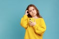 Portrait of little girl holding smart phone in hands, looking away with thoughtful facial expression Royalty Free Stock Photo