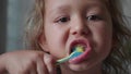 Portrait of little girl is intensively brushing her teeth in bathroom