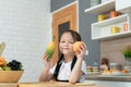 Portrait of a little girl in the kitchen of a house having fun playing with fruit toy Royalty Free Stock Photo