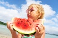 Portrait little girl licking fresh watermelon slice posing on beach having fun and positive emotion Royalty Free Stock Photo