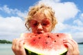 Portrait little girl licking fresh watermelon slice posing on beach having fun and positive emotion Royalty Free Stock Photo