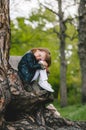 Portrait of little girl with long hair leaning on tree trunk at park in forest. Cute kid, nature lover concept Royalty Free Stock Photo