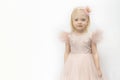 Portrait of little girl in lush pink dress with hoop crown on head. Blonde girl isolated on white background. Copy space