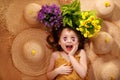 Portrait of a little girl lying on background with flowers and straw hat, summer and travel feeling concept