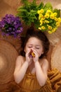 Portrait of a little girl lying on background from straw hats holding flowers in hands, summer and travel feeling concept