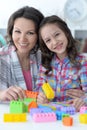 Portrait of little girl and mother playing with colorful plastic blocks at home Royalty Free Stock Photo