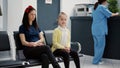 Portrait of little girl and mother sitting in waiting room area Royalty Free Stock Photo