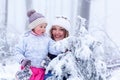 Portrait of a little girl and mother in winter hat in snow forest at snowflakes background Royalty Free Stock Photo