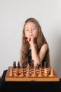 Portrait of little girl plays chess, thinking about game of chess on white background. Royalty Free Stock Photo