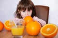 Portrait of a little girl plays with an oranges on a table. Happy little girl with glass of juice Royalty Free Stock Photo