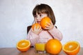 Portrait of a little girl plays with an oranges on a table. Happy little girl with glass of juice Royalty Free Stock Photo