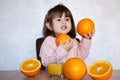 Portrait of a little girl plays with an oranges on a table. Happy little girl with glass of juice Royalty Free Stock Photo