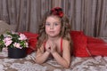 Little girl princess in a red dress and a hat sits on the sofa w Royalty Free Stock Photo