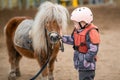 Portrait of little girl in protective jacket and helmet with her brown pony before riding Lesson Royalty Free Stock Photo