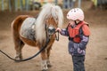 Portrait of little girl in protective jacket and helmet with her brown pony before riding Lesson Royalty Free Stock Photo