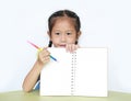 Portrait of little girl in school uniform show writing on blank notebook sitting at desk over white background Royalty Free Stock Photo