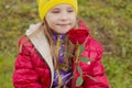 Portrait of a little girl. She sits on a bench and looks at the rose with a smile