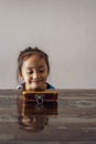 Portrait of a little girl sitting at the table with mobile phone in front of her. watching videos on the handphone Royalty Free Stock Photo